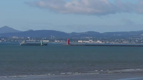 Cargo Ship Passing Red Lighthouse at Dublin Bay Entrance from Bull Island Stock Footage 345398223