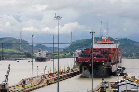 Cargo ship passing through the Panama Canal with shipping containers. Stock Photos