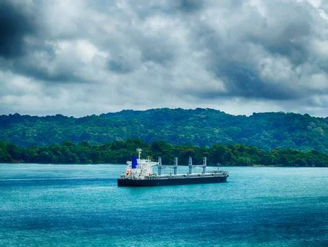 Cargo ship passing through the panama canal, enveloped by vibrant rainfores.. Foto stock