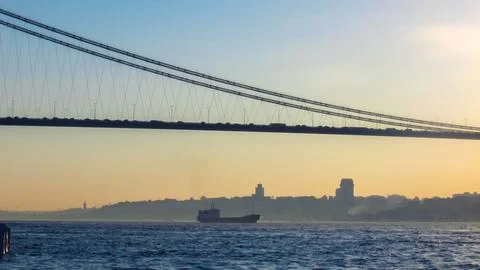 Cargo ship passing under the Bosphorus Bridge at sunset, Istanbul skyline vie Stock Photos