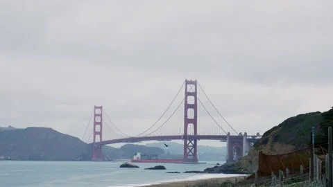 Cargo ship passing under the iconic Golden Gate Bridge seen from Baker Beach in Видео 197348580