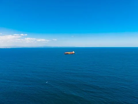 Cargo ship sailing on clear blue waters under a blue sky near the coast dur.. Stock-Fotos