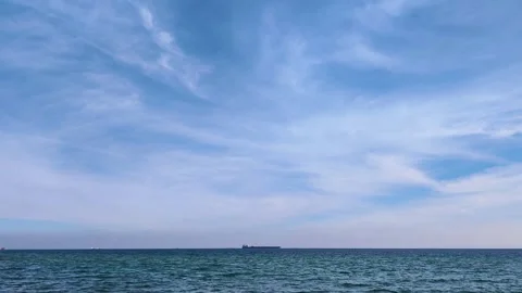 Cargo Ship Sailing on Deep Blue Ocean Under Bright Sky with Soft Clouds Stock Footage 340360711