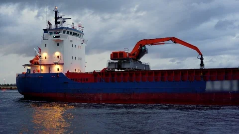 Cargo ship sailing into the harbor with dramatic dusk clouds in the background. Stock Footage 91338439