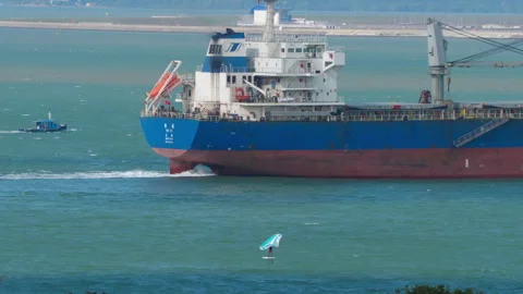 Cargo ship sailing near wing foiler in Singapore Strait Stockbeeldmateriaal 336896352