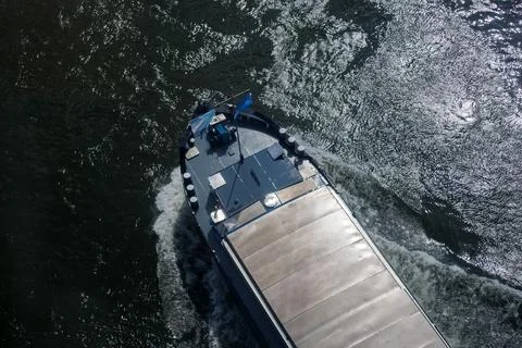 Cargo ship sailing on river with shimmering water viewed from above Stock-Fotos