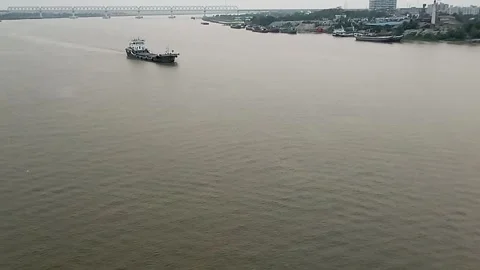 Cargo ship sailing on a wide river near the city Stock Footage 318694062