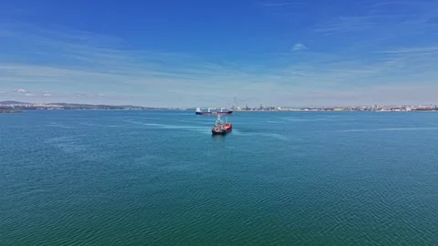 Cargo ship sails on calm waters near busy port Stock Footage 338404719