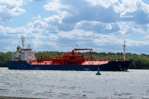 Cargo ship sails on river with green buoy and trees under cloudy sky during.. Fotos de archivo