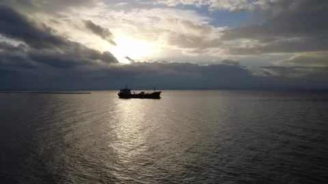 Cargo Ship Silhouette at Dusk Under Cloudy Sky at Sea Stock Footage 343997791