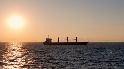 Cargo Ship Silhouette at Sunset Over Calm Sea, Golden Hour Maritime Scene Stock Footage 334794792