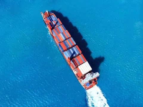 Cargo ship transporting containers import export to port on background of blue Stock Photos