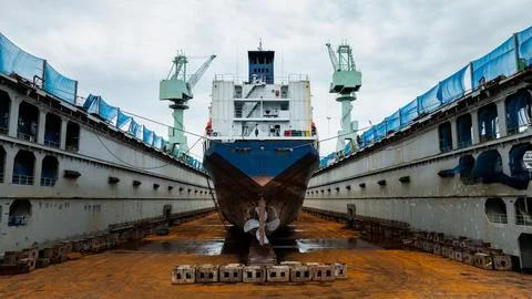 Cargo Ship Undergoing Maintenance In Dry Dock Facility Wide Shot Stock Photos