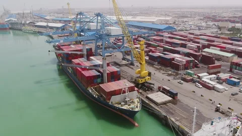 Cargo ship unloading containers at busy port in daylight hours Stock Footage 318205989