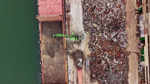 Cargo ship unloading scrap metal near the shoreline in a busy port 스톡 동영상 338324187