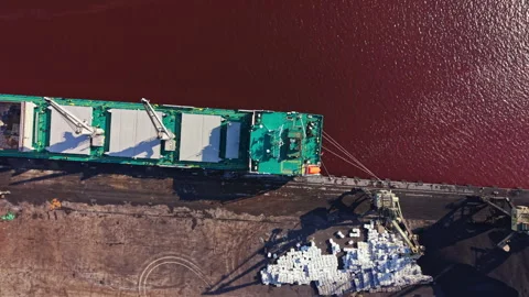 Cargo ship unloads materials at a river dock during daylight hours, with 스톡 동영상 340947166