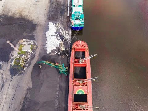 Cargo ships are at a loading dock near a river with equipment transferring .. Stock Photos