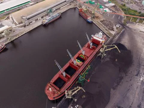 Cargo ships at port during loading process in industrial area Stock Photos
