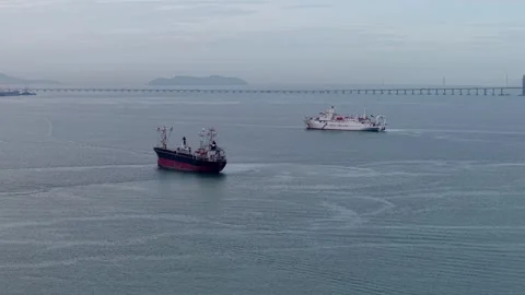 Cargo ships sailing on calm ocean near distant bridge and islands Stock Footage 336948823