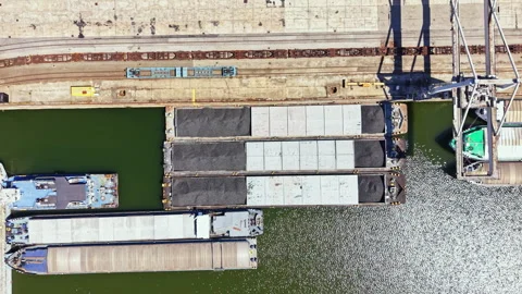 Cargo ships unload materials at a shipping dock near water during daytime at a Stock Footage 344248449