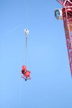 Cargo suspended on a hook of a construction crane against a blue sky backgrou Stock Photos