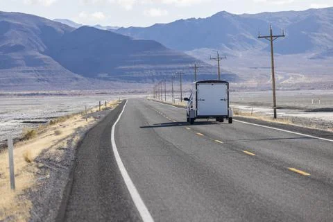 Cargo trailer being pulled down an empty highway stretching for miles into th Foto stock