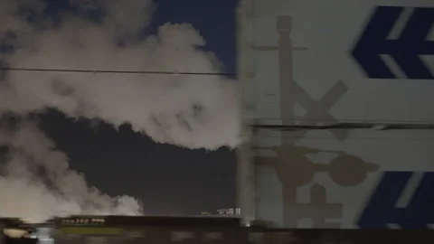 Cargo train containers speeding in front of factory at night Stock Footage 225499552