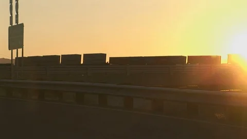 Cargo train passing by highway during sunset Stock Footage 105543549
