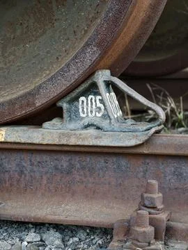 Cargo train wheel resting securely on brake chock preventing movement along.. Stock Photos