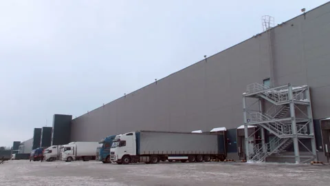 Cargo trucks loaded or unloaded from the warehouse complex in winter Stock Footage 105990270