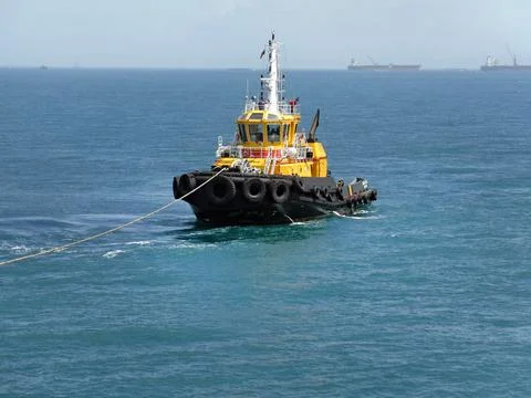 Cargo tug in the ocean pulls the ship into port Stock Photos