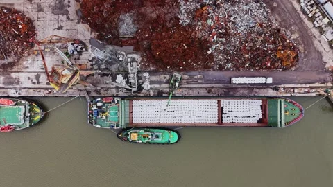 Cargo vessel loading at shipyard with nearby scrap materials 動画素材 337941994