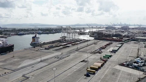 Cargoe ship docks beneath towering container cranes at Oakland port terminal Stock Footage 339907994