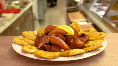 Caribbean fired pork whit fried green bananas on the restaurant counter Stock Footage 131919248