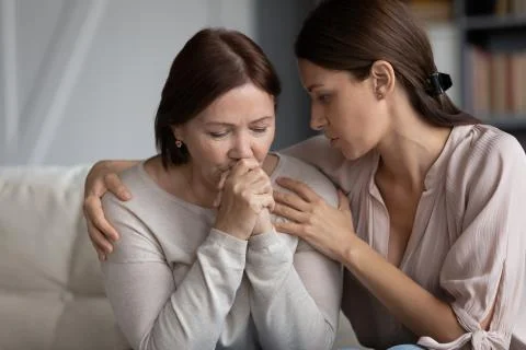 Caring adult daughter comforting sad middle aged mother Stock Photos