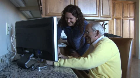 Caring caregiver/young woman looks at computer with elderly man-laughing Stock Footage