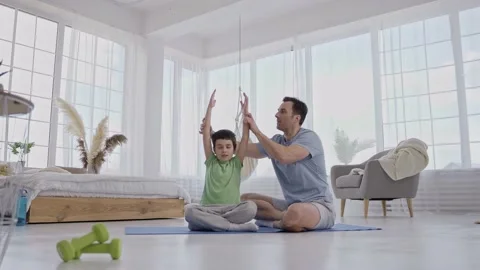 Caring dad helping son to keep yoga pose indoors Stock Footage 160940548