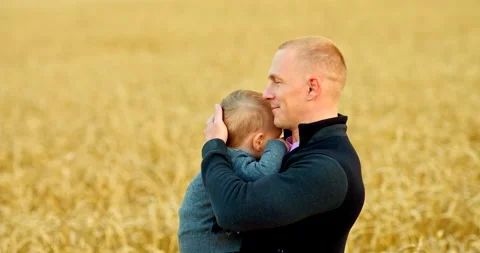 Caring dad holds his son in his arms and strokes his head, kisses and smiles Stock Footage 138969088