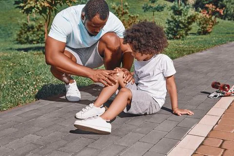 Caring dad looking at the knee of his child Stock Photos