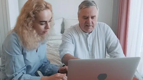 Caring daughter teaching elderly father how to use laptop and showing new Stock Footage 295225760