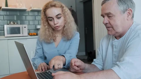 Caring daughter teaching elderly father how to use laptop, showing how to typing Stock Footage 295226036