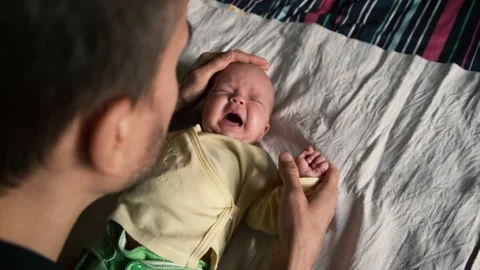 Caring father gently strokes head of upset cute crying newborn baby. Stock Footage 185687494