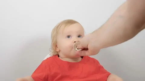 Caring father hand giving pacifier to little cute baby boy girl sitting in Video stock 155801019