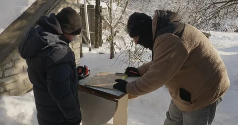 A caring father teaches his son woodworking skills. They build a bird feeder Video stock 328026273