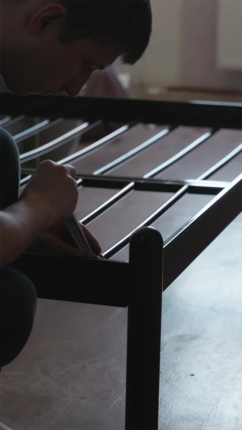 Caring father using tools to disassemble wooden bed for room upgrade Stock Footage 338003289