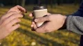 Caring guy treating his beloved with warm beverage to go during date in park 4k or 4k+ Resolution