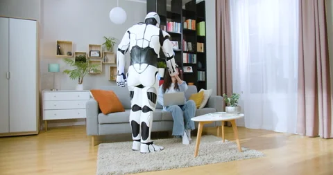 Caring human like robot bringing fresh organic apple to focused woman indoors Stock Footage 244140679