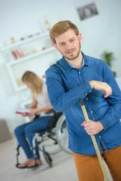 Caring husband cleaning home while disabled wife is relaxing Stock Photos