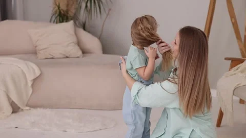 Caring loving mother dressing daughter in living room Stock Footage 245848853
