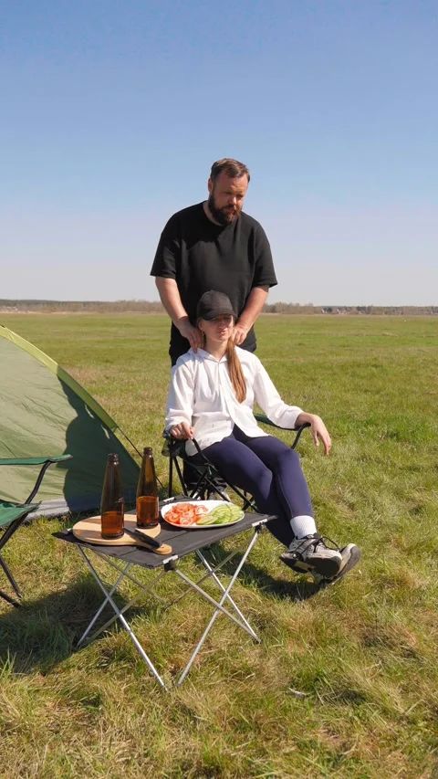 Caring man massaging woman's shoulders during camping trip Stockbeeldmateriaal 344605710